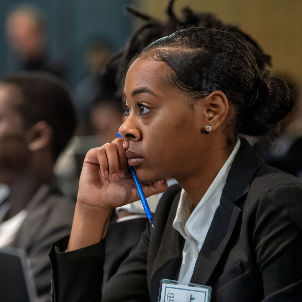 A female student in a suit listens to a lecture.